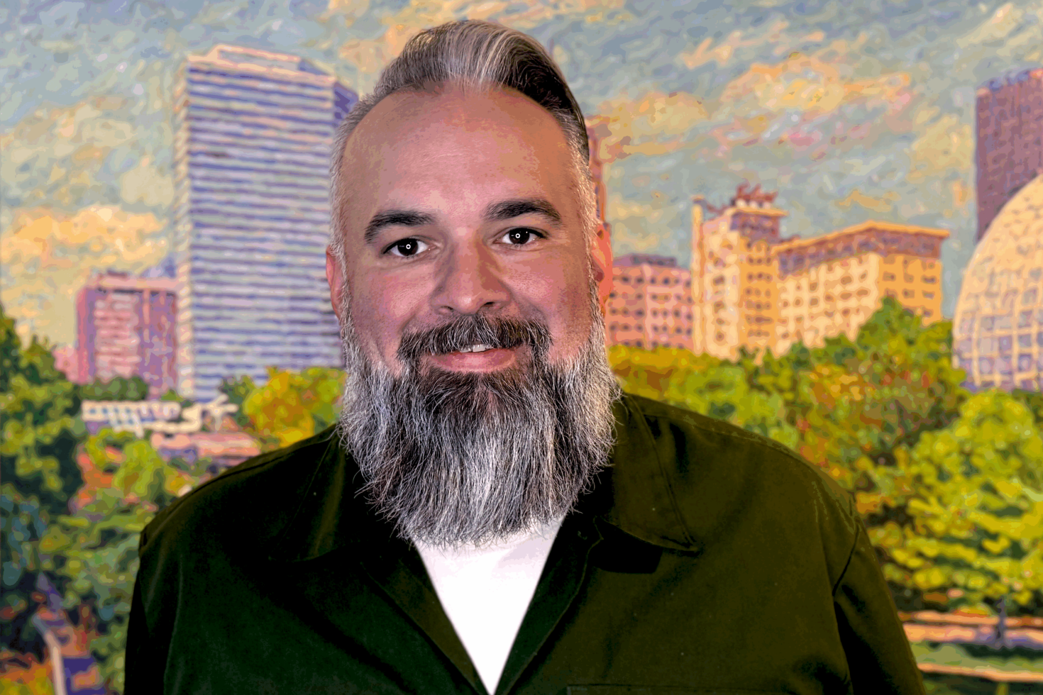 Bearded man in a black shirt smiling in front of a cityscape painting of Oklahoma City.