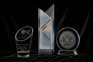 Three translucent awards on a black background: ONE non-profit excellence award, Hometown Heroes award, and Best of the 405 award.