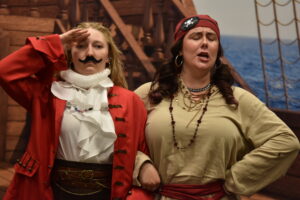 Two opera singers dressed as pirates pose on stage for kids at a summer library concert.