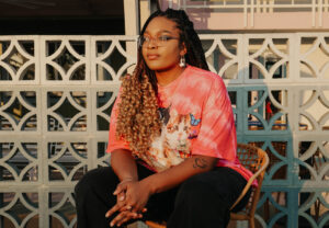 Teaching Artist Jasmine Jones sits at a 3/4 angle watching a sunset.