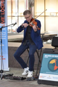 A man leaning on a fountain playing violin.