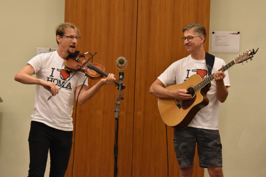 Two men in white shirts playing string instruments.