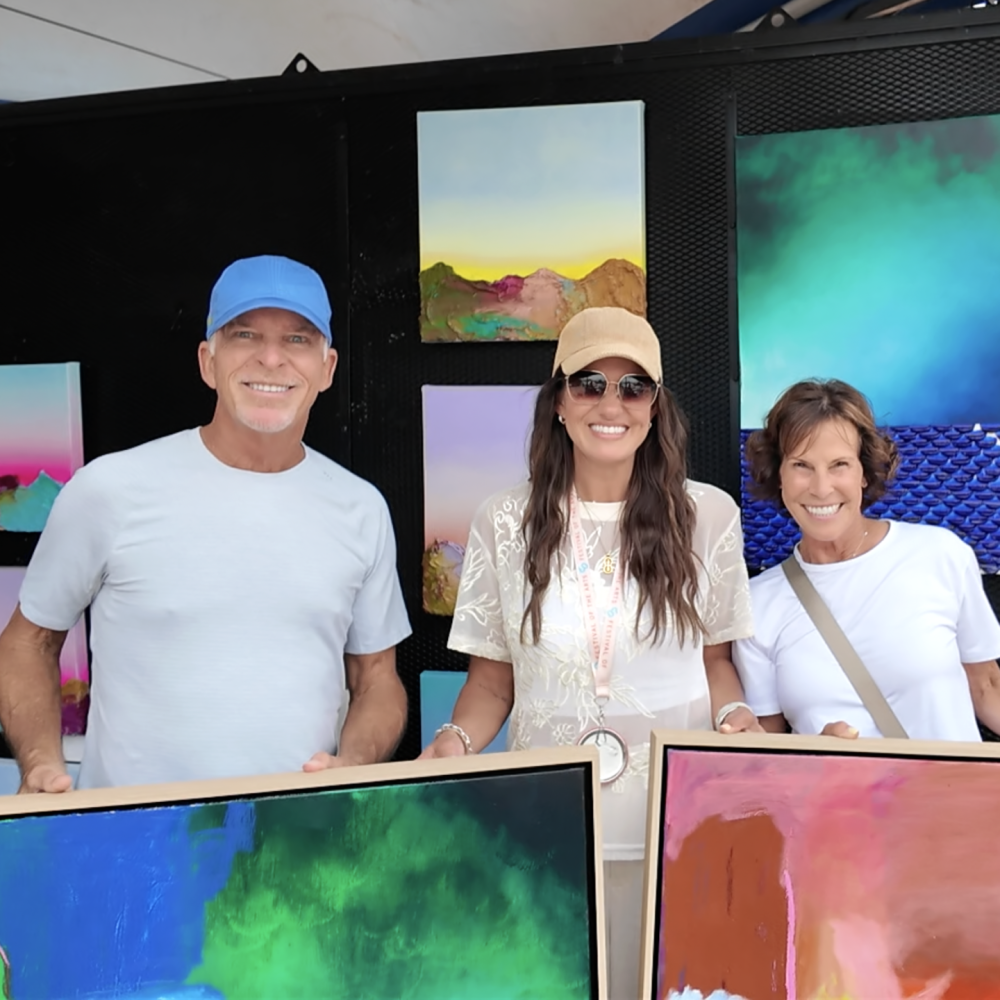 Painter Piper Bridwell standing with Festival of the Arts patrons after making a sale.
